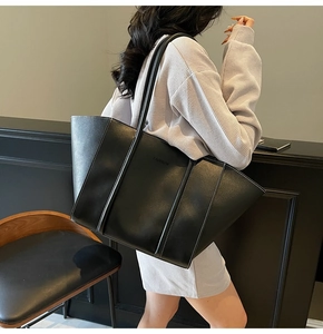 Detail of black tote bag with white contrast stitching and embossed fashion lettering