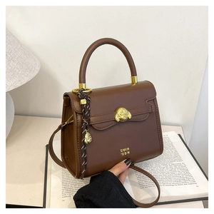 Detail of a brown leather crossbody bag featuring a golden dog clasp and chic accessories