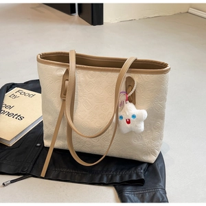 Close-up of cream embossed tote bag with floral patterns and a plush star charm detail
