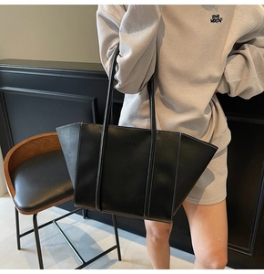 Detail view of black tote bag featuring contrast white stitching and fashion embossing