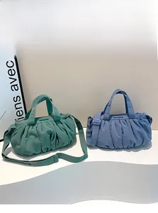 Detailstruktur der gefalteten Nylon-Cloud-Bags in Waldgrün und Nebelblau Tönen