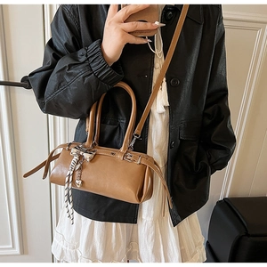 Brown Boston handbag featuring a metal bow charm and striped scarf on a model