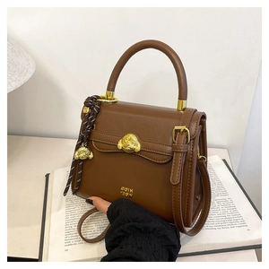 Detail of vintage brown leather bag featuring golden dog emblem and logo branding