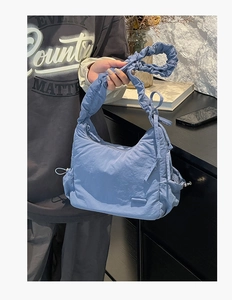 Primer plano de un bolso de hombro azul plisado con cordones y tejido de nailon