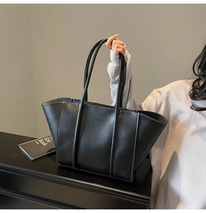 Detail of black tote bag featuring white contrast stitching and Fashion logo detail