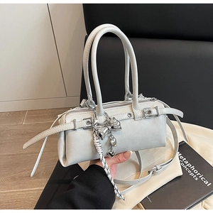 Detail of grey Boston bag with silver heart charm and bow accent on a sleek leather finish