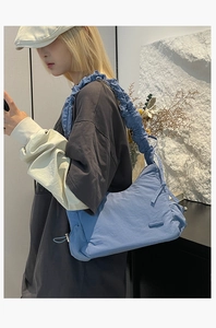 Bolso de hombro de nailon azul con correa fruncida mostrado por una modelo real