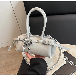 Detail view of light grey Boston bag with metal heart charm and buckle strap decor