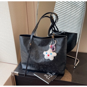 Detailed view of black embossed tote bag with Chinese characters and star plush charm