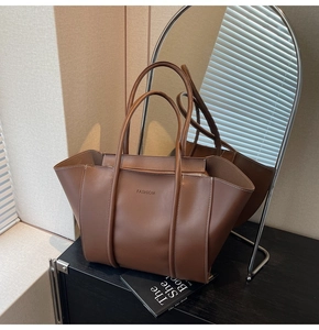 Detail of a large brown vintage tote bag with FASHION embossing and wing structure