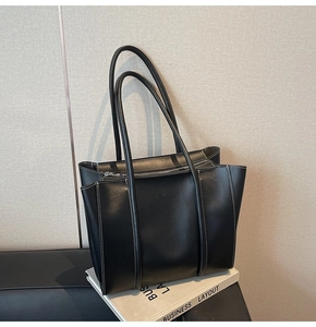 Close-up of black leather tote bag with white stitching and embossed FASHION text