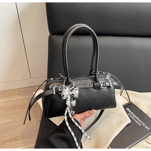 Detail of black matte Boston bag featuring silver bow charm and heart metal pendants