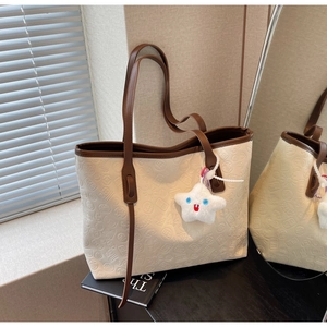 Detailed relief pattern on cream tote bag with brown leather trim and star charm