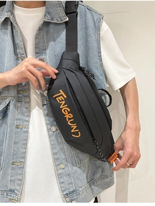 Détail de la sacoche bandoulière noire avec logo orange portée sur une veste en jean