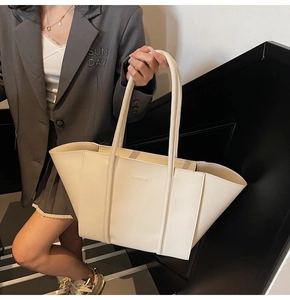 Detail of a large beige tote bag with side wings and FASHION logo shown on a model