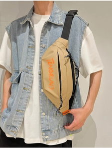 Détail du sac bandoulière kaki avec lettrage orange et tirettes de fermeture corde