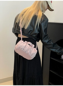 Nahaufnahme der rosa Plissee-Wölkchen-Tasche kombiniert mit einem schwarzen Outfit