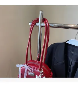 Gros plan d'un sac en cuir verni rouge avec un nœud en dentelle blanche et logo métal