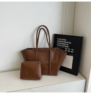 Close-up of brown faux leather tote set with white stitching and embossed logo detail