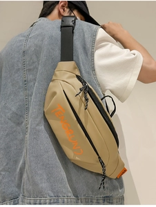 Gros plan d'un sac de poitrine en toile kaki avec lettrage orange porté par un mannequin