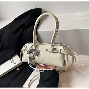 Detail of cream white Boston bag with silver bow charm and matte leather texture