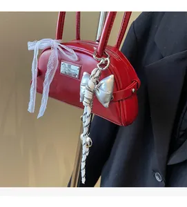 Gros plan du sac rouge brillant avec nœuds décoratifs et pendentifs métalliques argentés