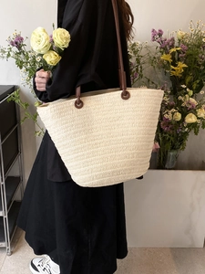Chic beige straw tote bag with brown leather straps shown on a model for summer