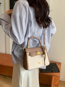 Elegant beige and purple crossbody bag with lion head ornament shown on a model