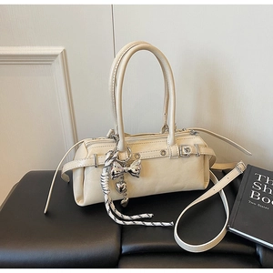 Detailed view of beige Boston bag featuring decorative heart charm and metallic accents