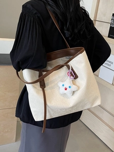 Large cream tote bag with embossed patterns and brown leather straps on model