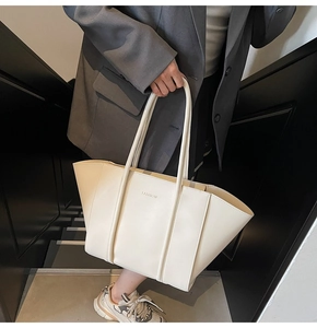 Close-up of cream white leather tote bag with FASHION letter print on a gray suit model