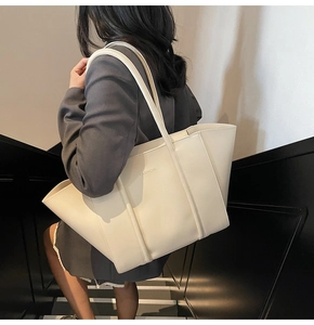 Close-up of cream white tote bag with FASHION text being worn by a model on stairs