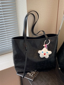 Black large leather tote bag with embossed traditional patterns and plush star charm
