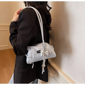 Détail du sac à main bleu clair avec bordure en dentelle et breloque nœud métallique