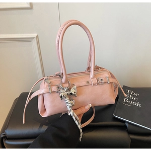 Detailed view of a pink cylinder Boston bag with silver bow charm and woven rope handle