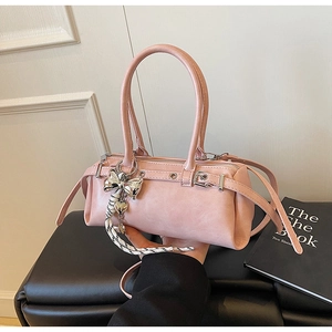Detail view of pink matte leather Boston bag with silver bow charm and carry handles