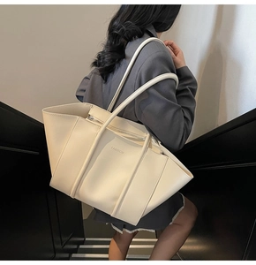 Model wearing a large beige matte leather tote bag with FASHION logo on a staircase