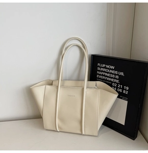 Detail of cream tote bag with embossed Fashion logo on smooth leather texture