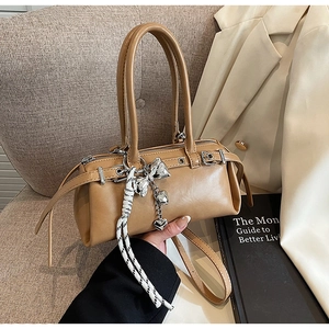 Detail of light brown Boston bag with silver heart charms on a beige sofa