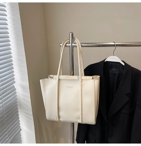 Detail of minimalist cream tote bag with embossed fashion text on high-quality leather