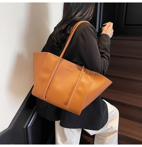 Close-up of tan leather tote bag with FASHION embossed logo in a street setting