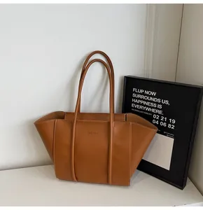 Detail of dark brown tote bag showing contrast stitching and embossed fashion logo