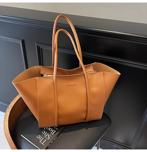 Detail shot of a brown large tote bag with folding design and embossed fashion logo