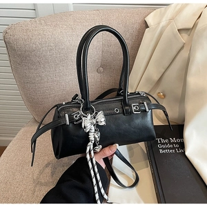 Detail of black Boston bag featuring silver buckle, eyelets and a bow charm accessory