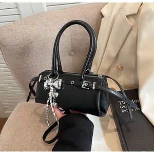 Detail of a black Boston bag with silver bow charms and metal buckles on a chair