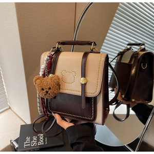 Detailweergave van mini-rugzak met gouden klinknagels en een berenkop-patroon