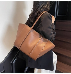 Brown leather tote bag shown from side back view on shoulder for size reference