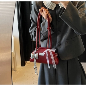 Détail du sac sous le bras bordeaux avec nœud en dentelle blanche et pendentif argent