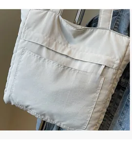 Detail showing the light grey soft fabric texture and large front pocket of the tote bag
