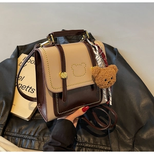 Detailopname van mini-rugzak met gouden beer-klinknagels en een zachte pluche hanger